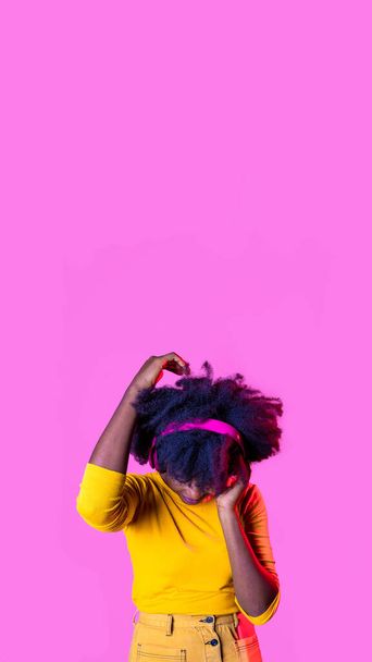 Junge lockige Haare schwarze Frau isoliert tanzen Musik hören mit drahtlosen Kopfhörern isoliert auf Werbung Copyspace Hintergrund - Foto, Bild