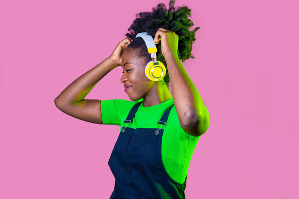 Fiatal göndör haj fekete nő elszigetelt tánc zenét hallgat vezeték nélküli fejhallgató - Fotó, kép