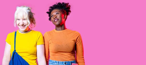 Two young diverse multicultural caucasian and black women best friends posing isolated background having fun laughing - Foto, Bild