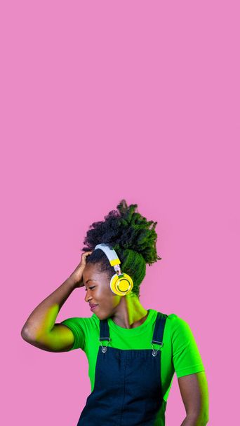 Joven cabello rizado mujer negra aislada bailando música escucha con auriculares inalámbricos publicidad copia espacio fondo - Foto, imagen