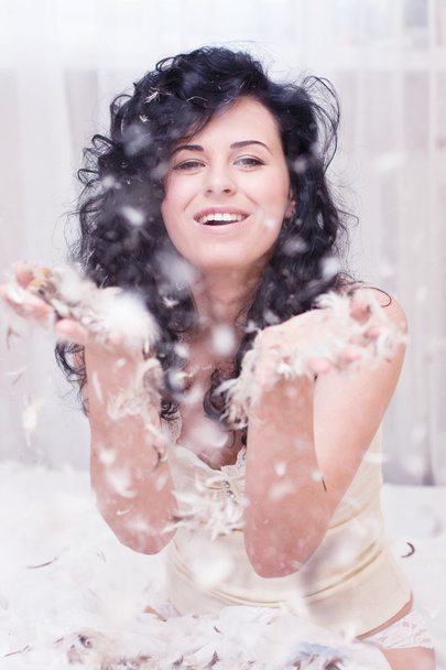 Sorridente giovane donna con piume su un letto
 - Foto, immagini