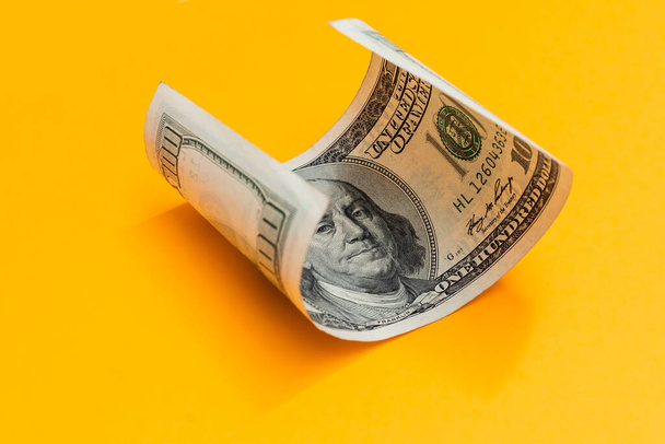 Single Hundred Dollar Bill Curled on yellow - Φωτογραφία, εικόνα