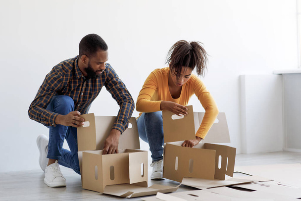 Busy millennial african american husband and wife preparing for move, stack cardboard boxes for things - Photo, Image