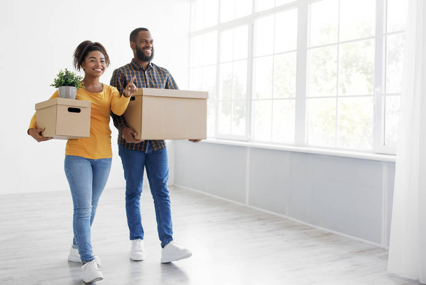 Cheerful millennial african american couple enjoying moving in new apartment, excited family in moving day - Photo, Image