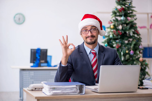 Giovane dipendente maschile che celebra il Natale sul posto di lavoro - Foto, immagini