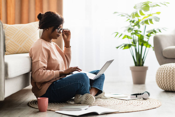 Musta Millennial Lady käyttäen laptop yllään silmälasit työskentelevät kotona - Valokuva, kuva