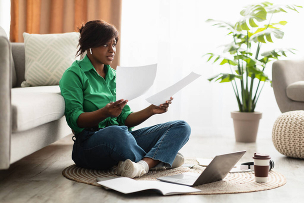Нещаслива африканська жінка читає негативні листи сидячи на ноутбуці в приміщенні
 - Фото, зображення
