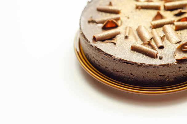 Digestive biscuit base with chocolate cheesecake and pockets of salted caramel sauce, topped with chocolate ganache, milk chocolate curls, and gold shimmer, the chocolate and salted caramel cheesecake - Photo, Image