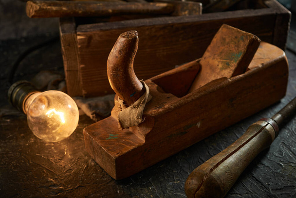 Дерев'яна коробка інструментів використовуваних ручних інструментів зі старими та брудними, іржавими гайковими ключами, молотками та старою лампочкою
 - Фото, зображення