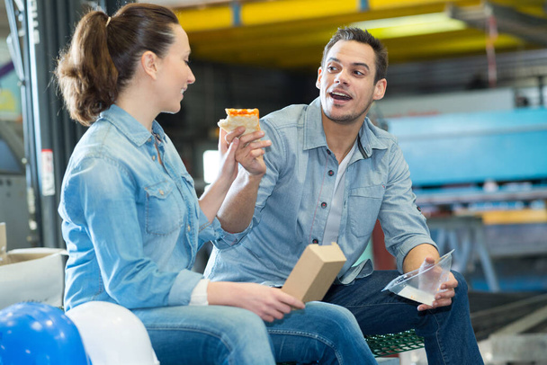 worker eating sandwich and talking to his colleague - 写真・画像
