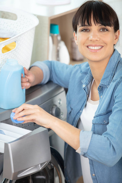a happy woman pouring detergent - Foto, afbeelding