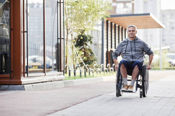 Mann im Rollstuhl geht ins Freie - Foto, Bild