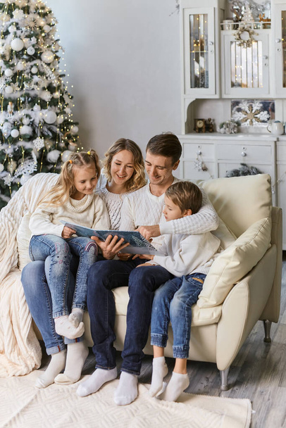 family, childhood, holidays and people - smiling mother, father and little kids reading book over lights background - Foto, Imagen