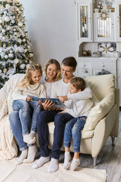rodzina, dzieciństwo, wakacje i ludzie - uśmiechnięta matka, ojciec i małe dzieci czytające książki na tle światła - Zdjęcie, obraz