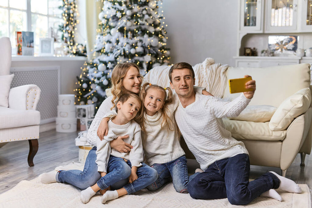 Joulun, lomien, teknologian ja ihmisten käsite onnellinen perhe istuu olohuoneessa ja ottaa selfie-kuvan älypuhelimella kotona - Valokuva, kuva