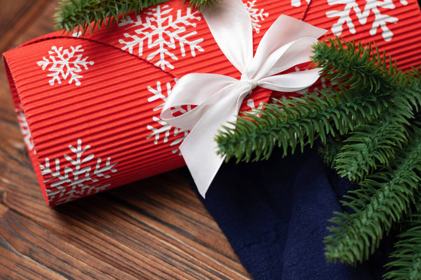 Christmas gift in craft packaging with a white bow with fir tree branches on a wooden background. - Photo, Image