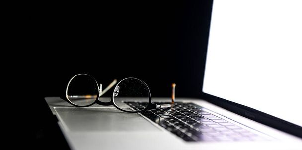 Szemüveg közeli a laptopon a sötétben. - Fotó, kép
