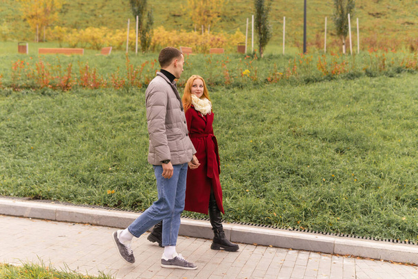 молодая пара, гуляющая и разговаривающая в осеннем парке - Фото, изображение