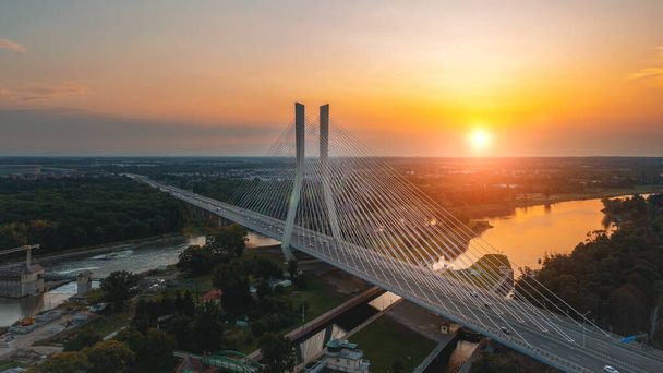 Große Brücke mit Masten vor dem Hintergrund der untergehenden Sonne. Redzinski-Brücke, Breslau Polen - Foto, Bild