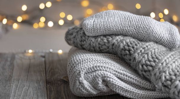 Уютный зимний фон со стопкой вязаных свитеров и огней, копировальное пространство. - Фото, изображение