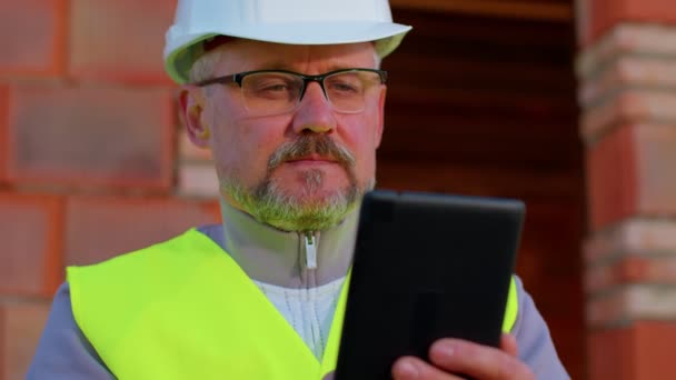 Architetto uomo con computer tablet digitale in cantiere, analizzando cianografie edificio - Filmati, video