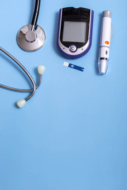 Medical concept on blue background stethoscope, lancet handle, glucometer. Vertical photo, close up with copy space. Diabetes concept. Flat layout. - Photo, Image