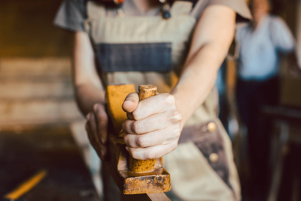 Primo piano sulla mano della donna falegname con pialla in legno
 - Foto, immagini