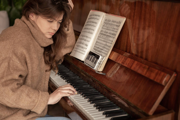 Una donna impara a suonare il pianoforte usando un'applicazione sul suo telefono. - Foto, immagini