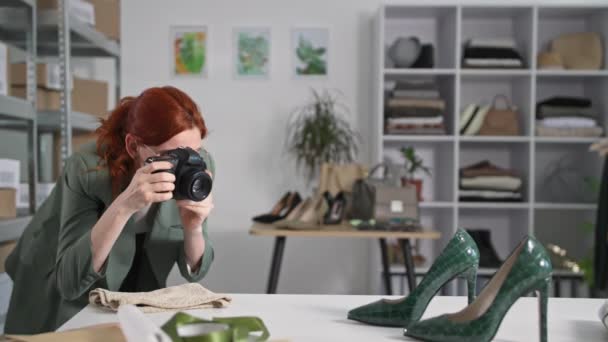klein bedrijf, jonge lachende vrouw met een DSLR camera maakt foto van goederen voor website en sociale netwerken van internet winkel achtergrond van boetiek - Video