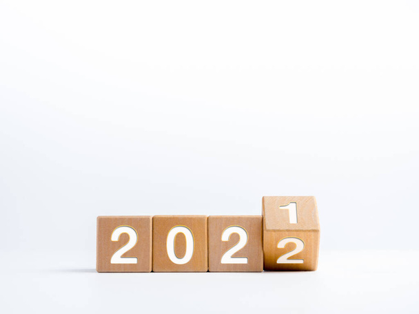 Tourner les numéros d'année pour le changement de l'année civile 2021 changé à 2022 sur des blocs de cube en bois isolés sur fond blanc avec de l'espace de copie, simple, propre et de style minimal. - Photo, image