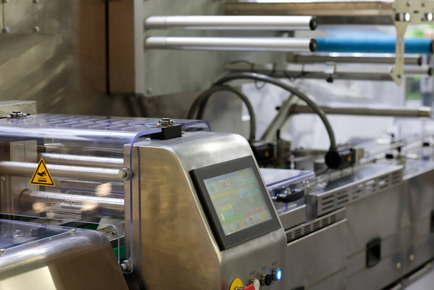 Automatic food packaging line with control panel of wrapping machine in foreground. Selective focus. - Photo, Image
