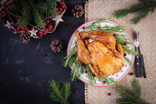 Gebackenes Huhn oder Truthahn. Der Weihnachtstisch wird mit Truthahn serviert, der mit hellem Lametta dekoriert ist. Gebratenes Huhn, Tisch vorhanden. Weihnachtsessen. Tisch gedeckt. Ansicht von oben, oben - Foto, Bild