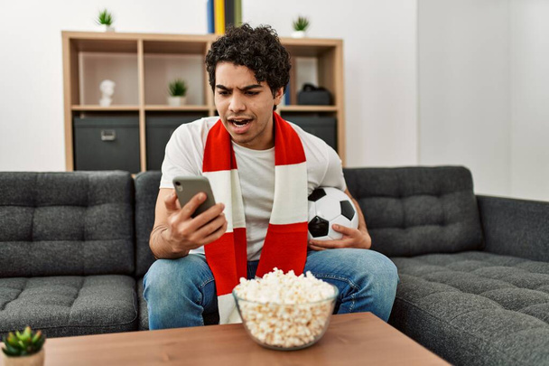 Молодий іспаномовний чоловік дивиться футбольний матч і допоміжну команду вдома
. - Фото, зображення