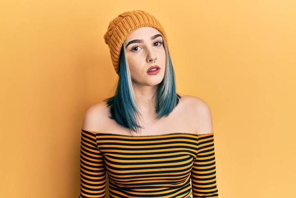 Jovem menina moderna usando chapéu de lã relaxado com expressão séria no rosto. simples e natural olhando para a câmera.  - Foto, Imagem
