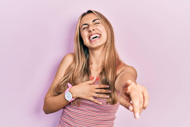 Schöne hispanische Frau in lässigem Sommer-T-Shirt, lachend, Zeigefinger in die Kamera mit der Hand über dem Körper, beschämender Ausdruck  - Foto, Bild