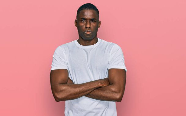 Young african american man wearing casual white t shirt skeptic and nervous, disapproving expression on face with crossed arms. negative person.  - Photo, Image