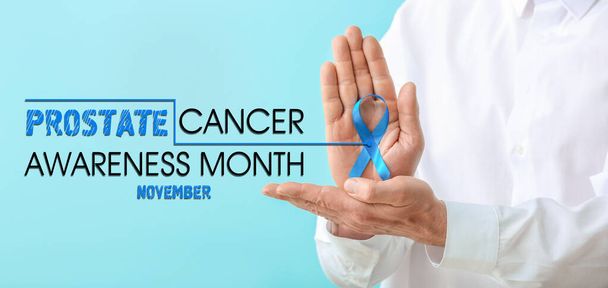 Doctor with blue ribbon and text PROSTATE CANCER AWARENESS MONTH NOVEMBER on color background  - Photo, Image