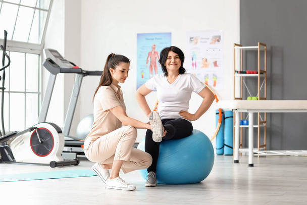 Femme mûre formation avec fitball et physiothérapeute dans le centre de réadaptation - Photo, image