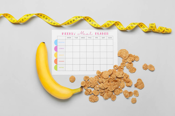 Plan de comidas con plátano, copos de maíz y cinta métrica sobre fondo claro - Foto, Imagen