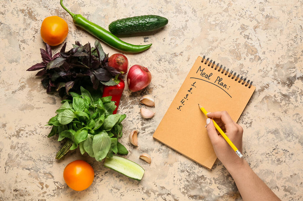 Женщина готовит план питания на цветном фоне - Фото, изображение