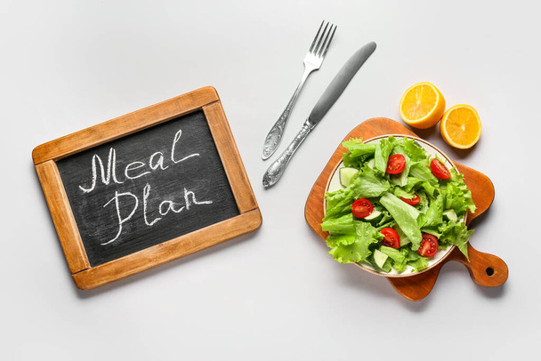 Chalkboard with words MEAL PLAN and fresh salad on white background - Photo, Image
