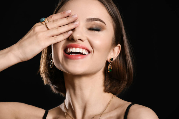 Молодая счастливая женщина с красивым маникюром и стильными аксессуарами на черном фоне - Фото, изображение