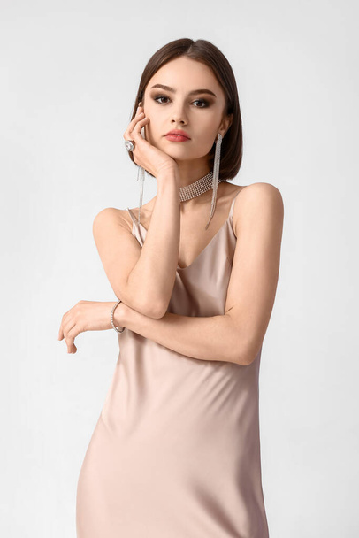 Young woman with elegant jewelry on white background - Φωτογραφία, εικόνα
