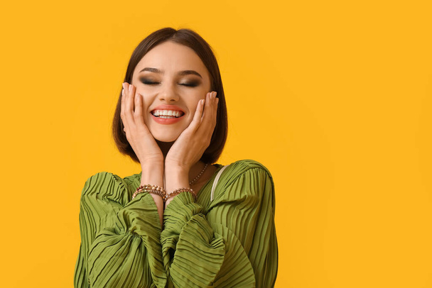 Glimlachende vrouw met trendy accessoires op kleur achtergrond - Foto, afbeelding
