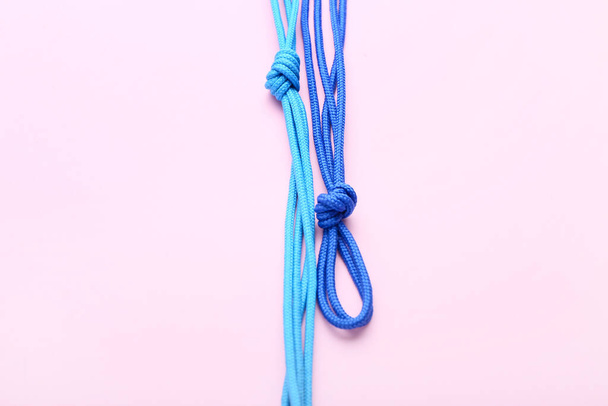 Blue shoe laces tied in knots on pink background, closeup - Foto, Imagem