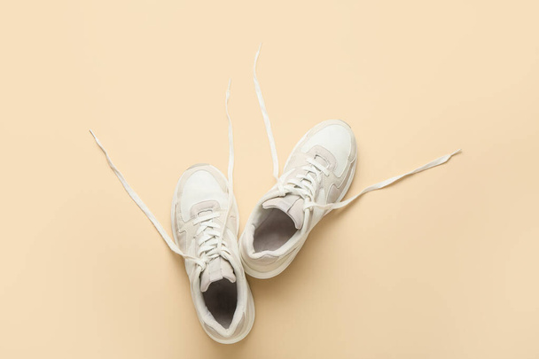 Sportive shoes with untied laces on color background - Photo, Image