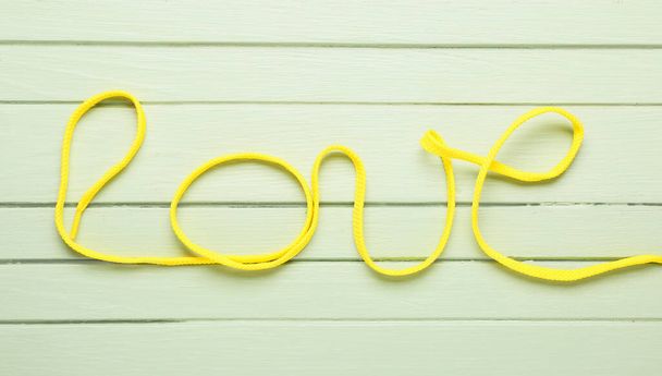 Word Love made of shoe lace on color wooden background - Photo, Image