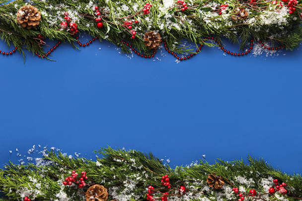 Christmas composition with coniferous branches, decorations and snow on blue background - Photo, Image