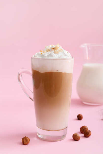 Glass cup of tasty latte with nuts on pink background - Foto, Imagem