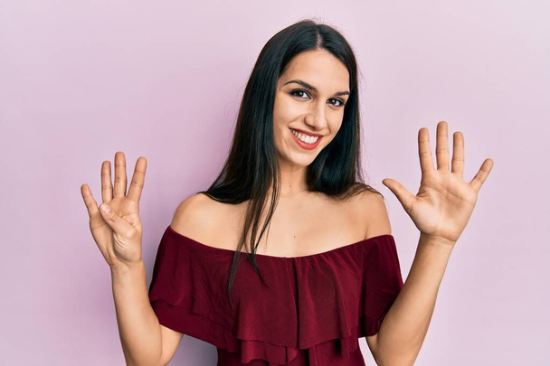 Young hispanic woman wearing casual clothes showing and pointing up with fingers number nine while smiling confident and happy.  - Φωτογραφία, εικόνα